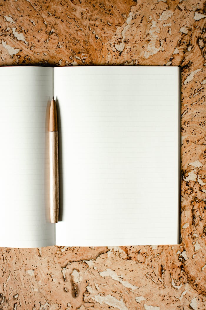 Mastering the First Impression: Your intriguing post title goes here Open notebook with wooden pen on a cork-textured surface, ideal for stationery mockups.
